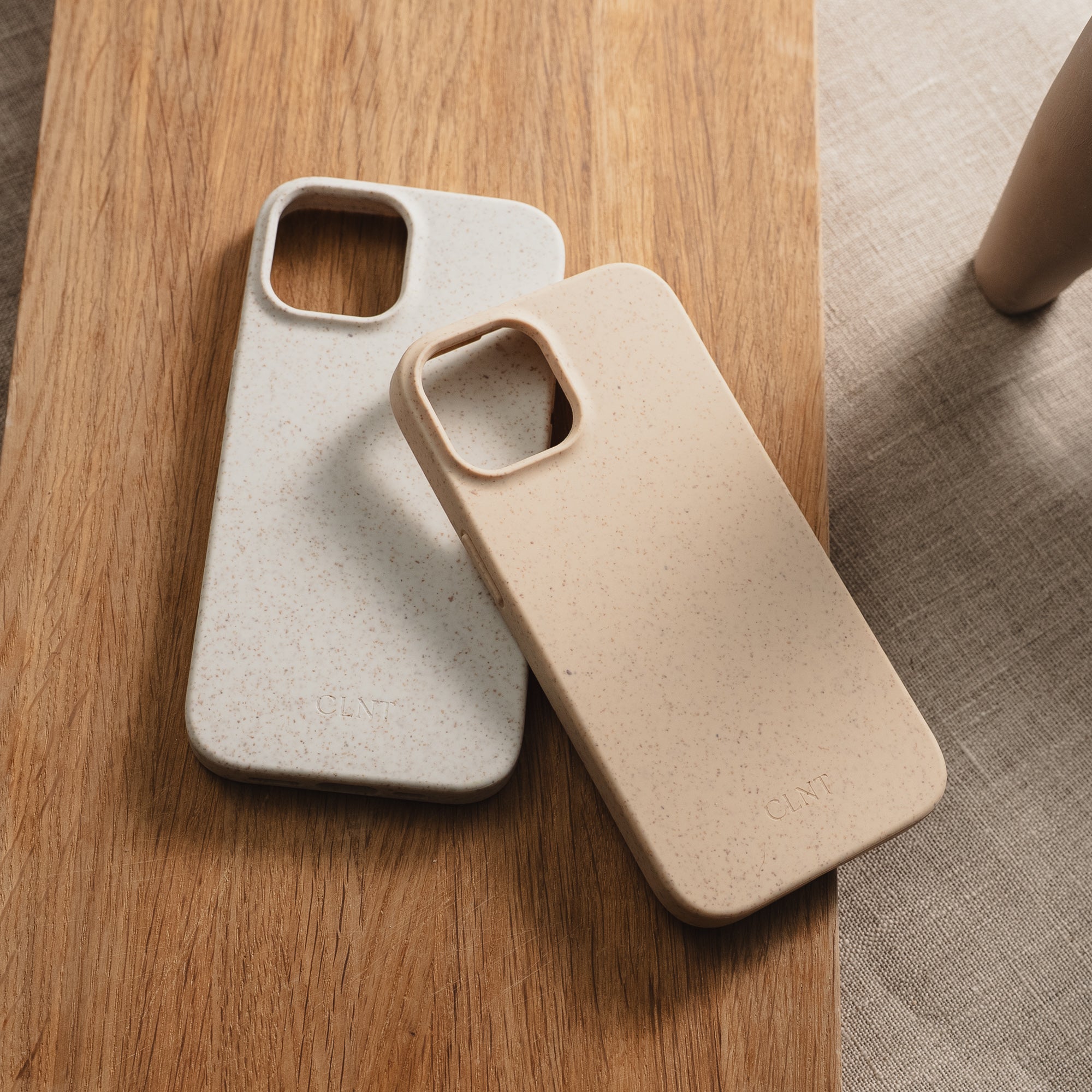 Grått og beige deksel til iphone fra CLNT - vist liggende uten mobilen på en stor fjøl
