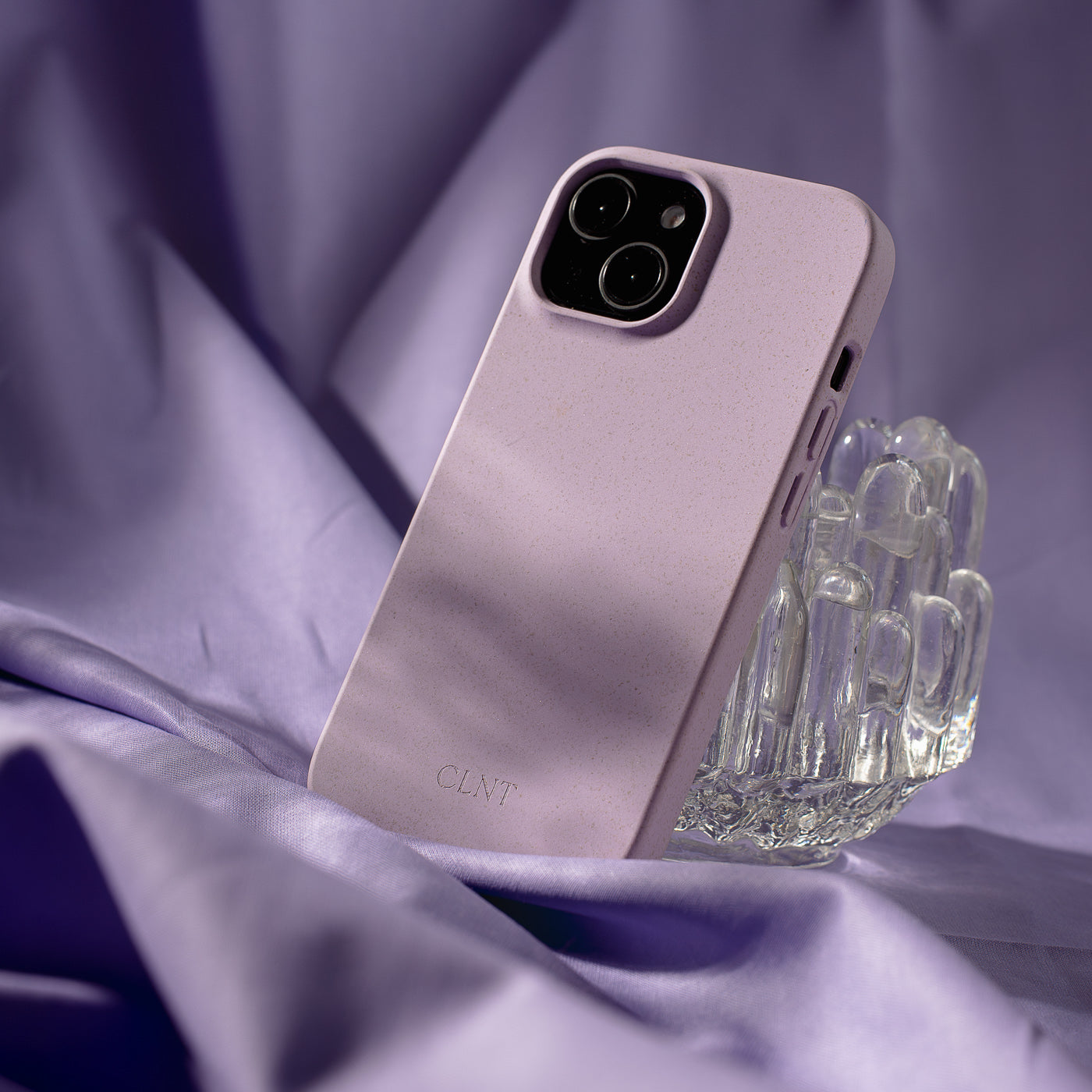 Nærbilde av et lilla deksel til iPhone fra CLNT  - vist med lilla bakgrunn støttende seg til et glass.