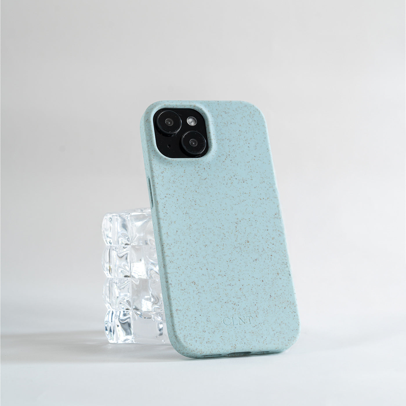 Lyseblått iPhone deksel fra CLNT som hviler på et glass