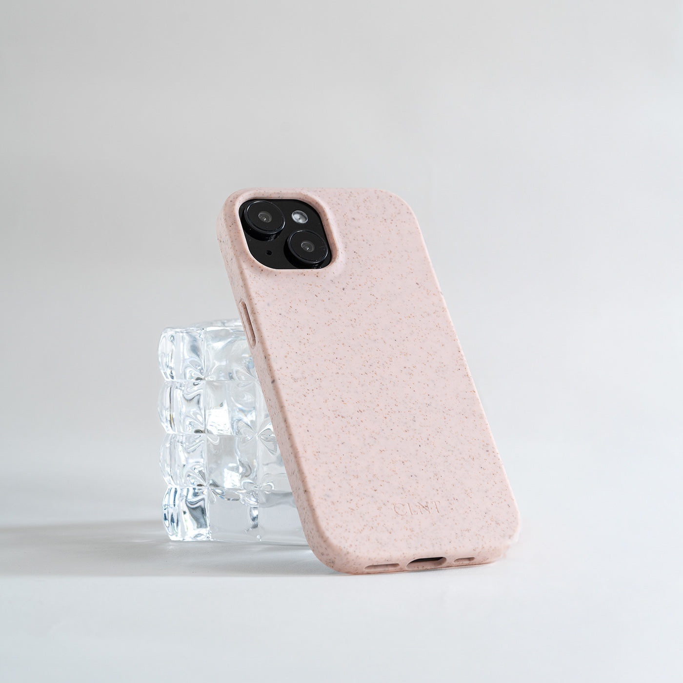 Rosa iphone deksel fra CLNT som hviler på et glass