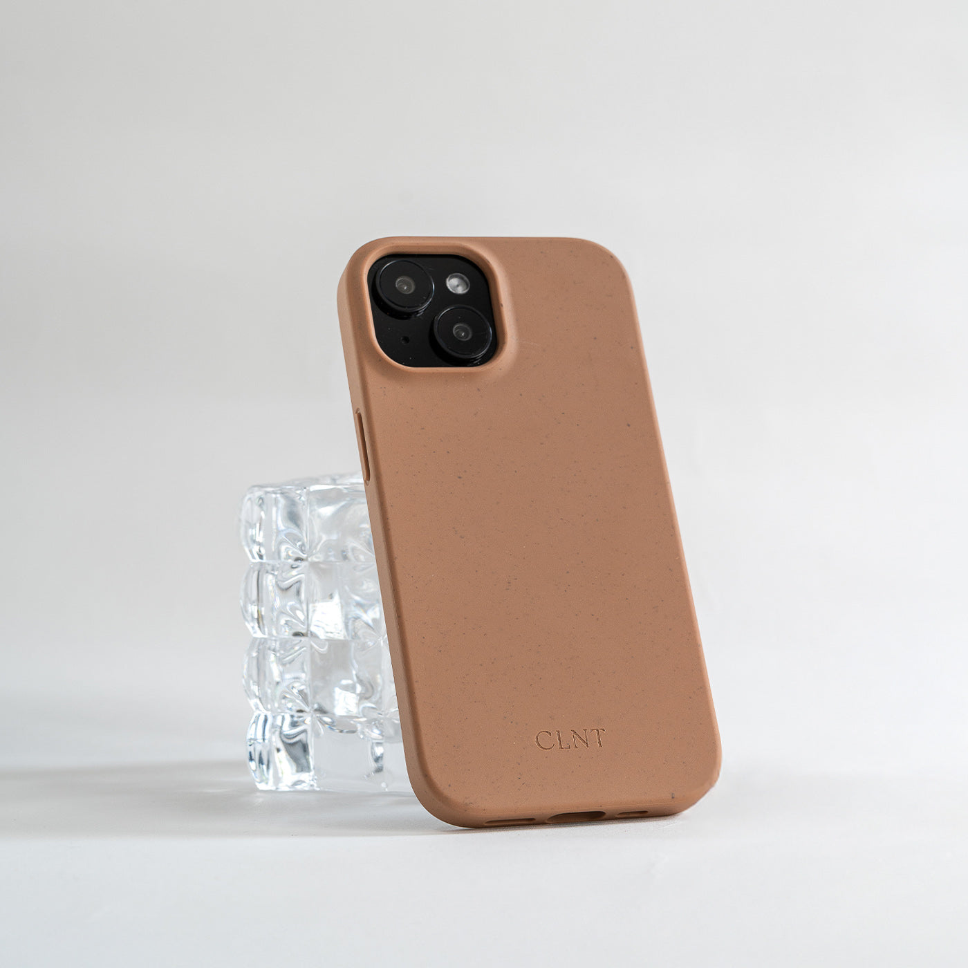 Rustfarget iphone deksel fra CLNT som hviler på et glass